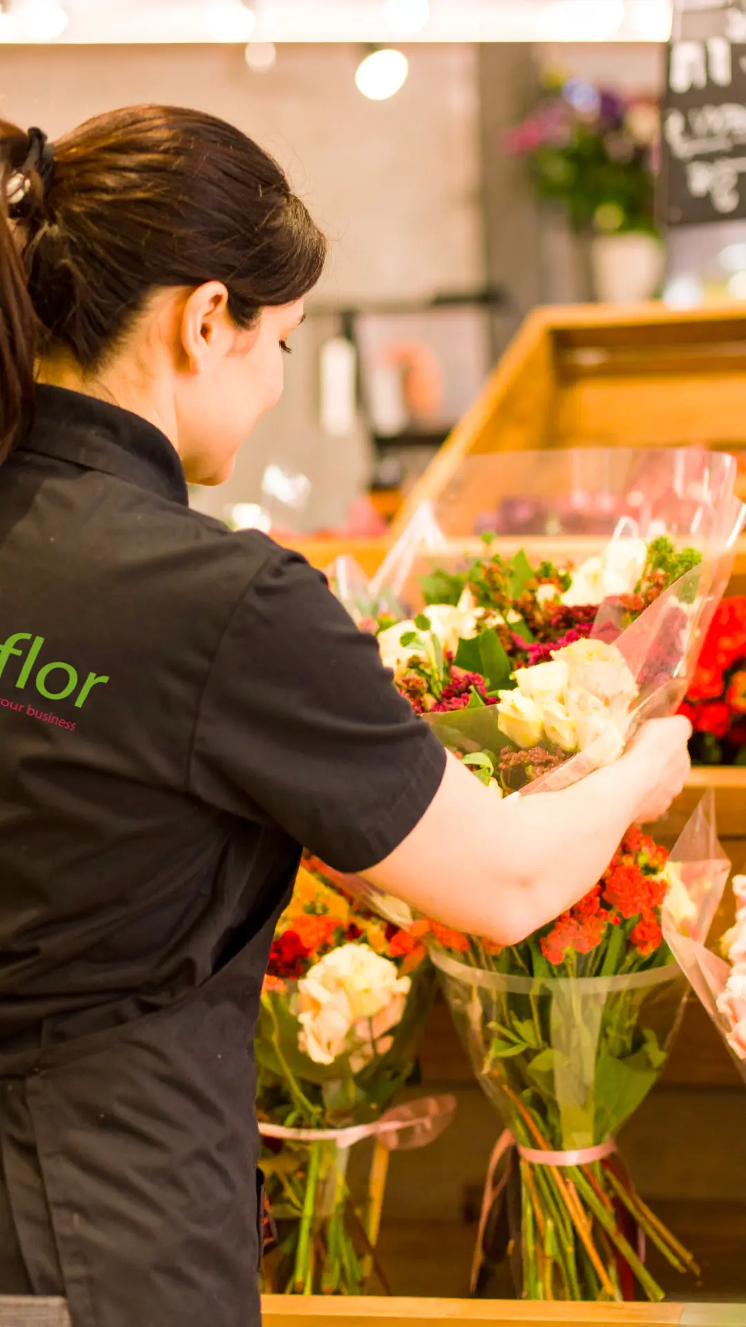 Fleuriste Comflor préparant un bouquet sur un étal de rayon